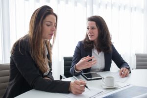 women in black blazer sitting near the table while having conversation