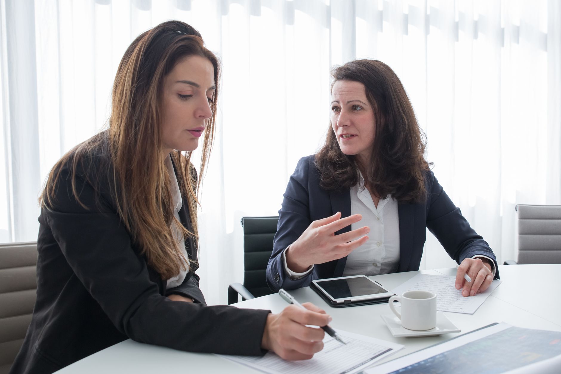 women in black blazer sitting near the table while having conversation
