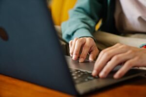 crop remote worker typing on laptop in house